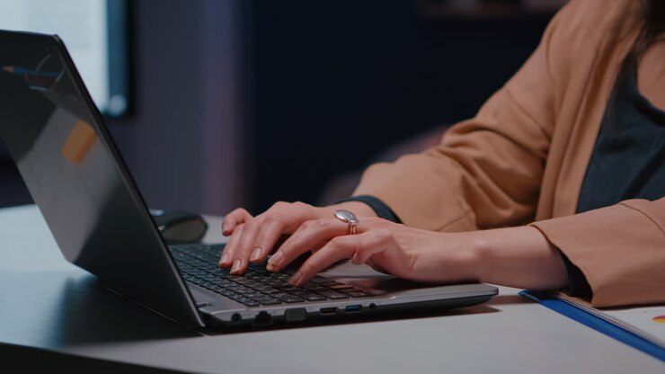 Nahaufnahme der Hände einer Geschäftsfrau an der Tastatur, die an einem Schreibtisch in einem Start-up-Büro sitzt