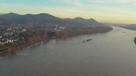 cinematic drone -aerial shot of the river rhine with a ship and the panorama of the seven mountains - siebengebirge königswinter - bonn at golden hour, 24p