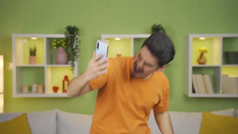 Happy-and-lively-young-man-using-phone-while-dancing.