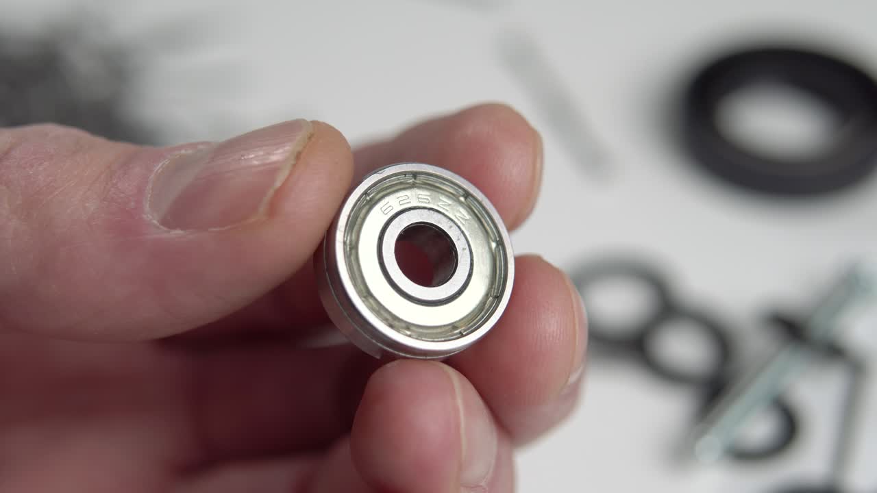 pequeño soporte de acero de la máquina en el hombre de servicio mano de cerca. macro. contra el fondo de piezas de repuesto y herramientas de reparación