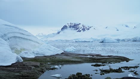 Paisaje-Costero-De-Montañas-Invernales-En-La-Antártida,-Paisaje-Azul-Frío-Con-Hielo-Glaciar-Y-Agua-De-Mar-En-La-Costa,-Paisaje-Marino-De-La-Península-Antártica-En-Una-Hermosa-Escena-Dramática