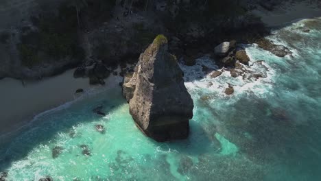 Luftaufnahme-Des-Kristallblauen-Wassers-Von-Diamond-Beach-In-Nusa-Penida,-Indonesien-Mit-Einer-Markanten-Großen-Klippe-Im-Vordergrund