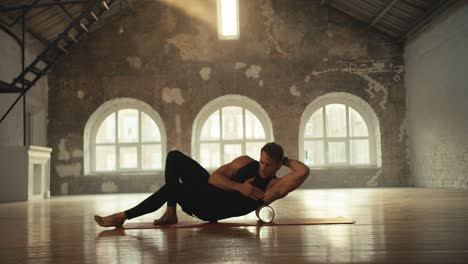 a man in a sports summer uniform is stretching with a special sports cone. sports brick hall lit by the rays of the sun