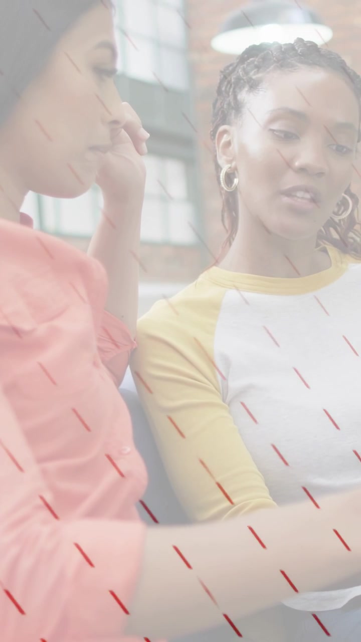 Vertical video: Women leaning over tablet right woman pointing overlaying screen for design