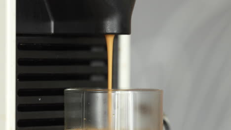 vista en primer plano de una máquina de café dispensando una corriente de café en una taza