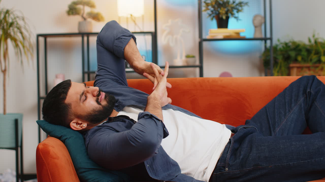 Tired bored arabian man sleeping enjoying carefree peaceful weekend relaxation on sofa at home room