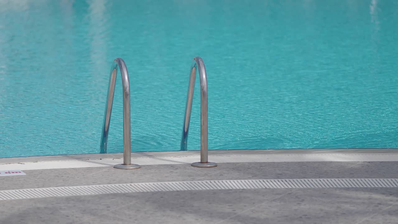 Klart blåt poolvand med metalgelændere