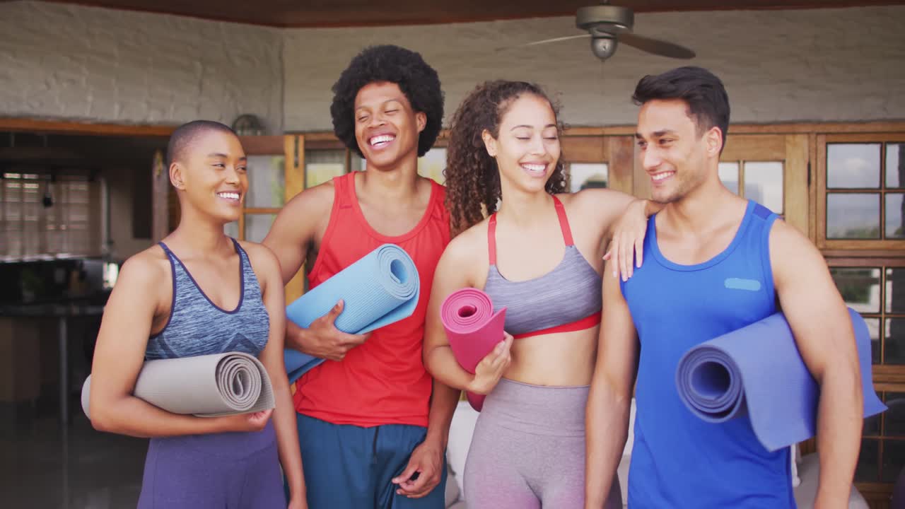grupo de diversos amigos masculinos y femeninos sosteniendo esteras de yoga y riendo