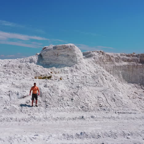 aerial view on white canyon and a sportsman outdoors. young athlete walking on beautiful white hill on the natural background in summer. shirtless athlete in shorts under blue sky.