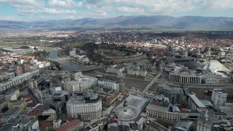 Vista-De-Drones-De-La-Ciudad-De-Skopje-Cruzando-El-Río-Vardar-Desde-Arriba,-Una-Ciudad-Histórica-Y-Turística