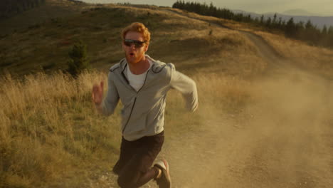 fit sportsman running fast on dirty road. athletic man jogging in mountains