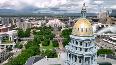 aerial past gold dome of colorado state capitol toward civic center park gathering of crowds for nuggets championship parade, denver, colorado