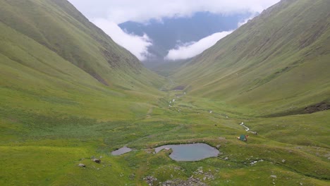 Aerial-shot-of-small-lake-in-the-middle-of-green-mountains