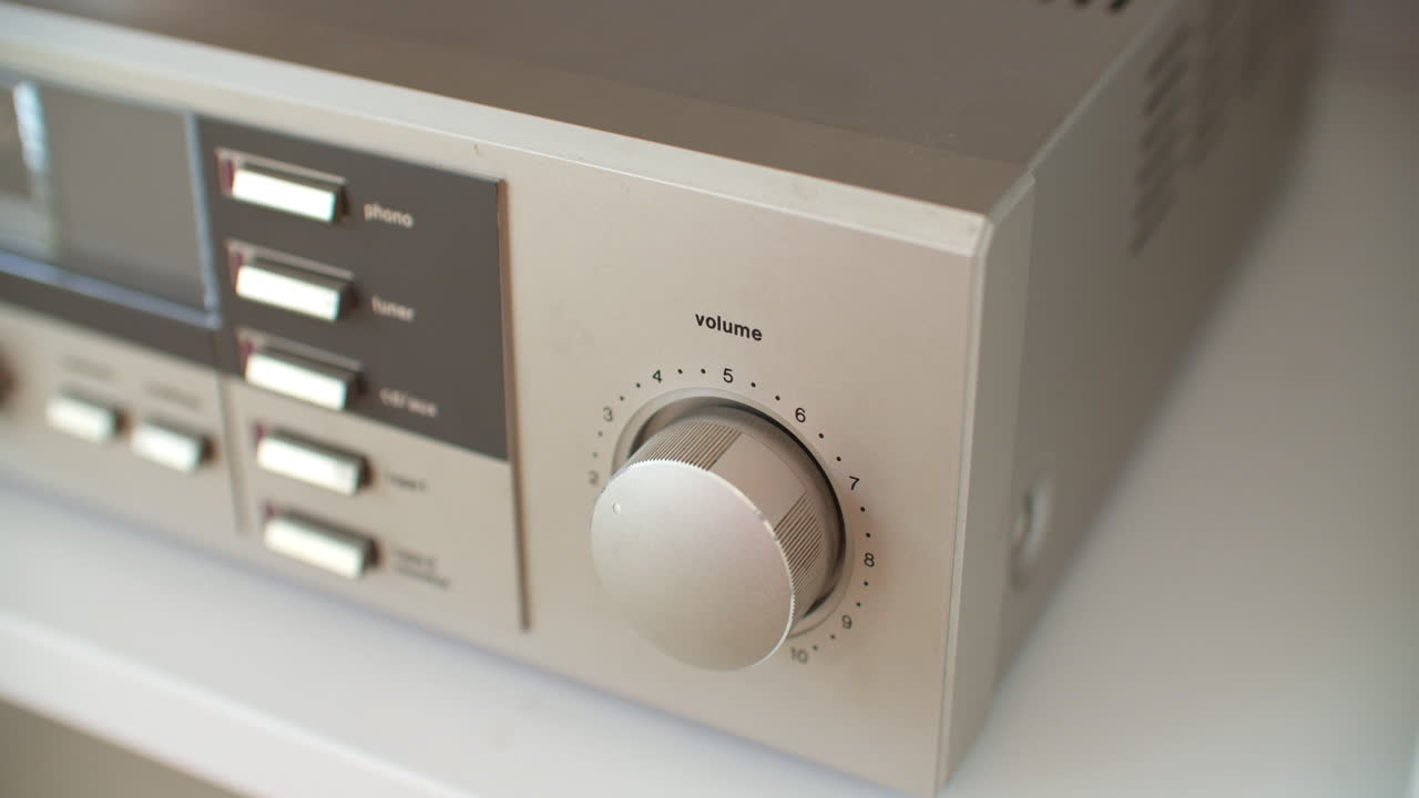 거실에 있는 스테레오 시스템의 볼륨 노브를 조정하는 높은 각도의 클로즈업 샷