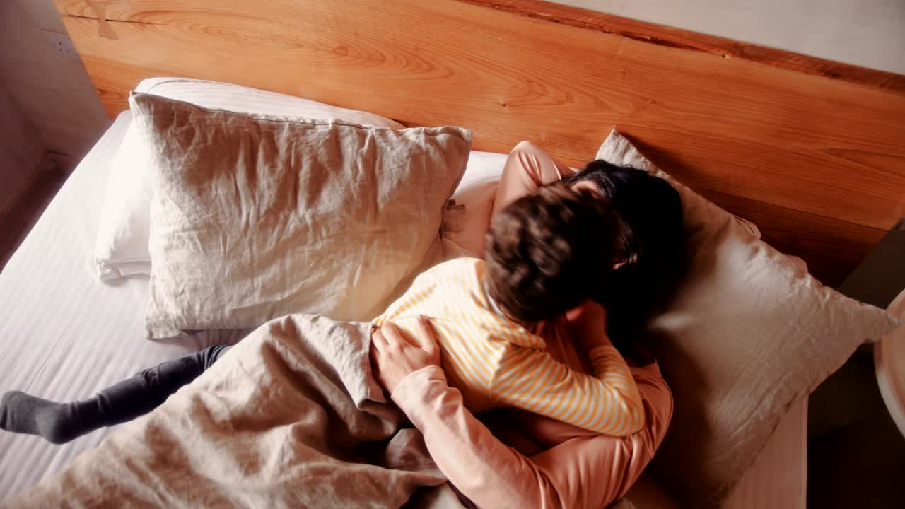 Mother and young son embracing in bed in the morning