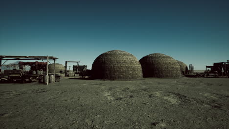 a desolate desert landscape with three dome-shaped structures in the distance