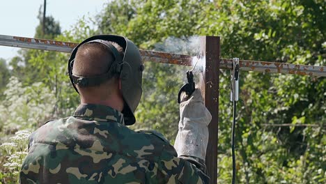 slow motion backside man builds fence using tool at sparks