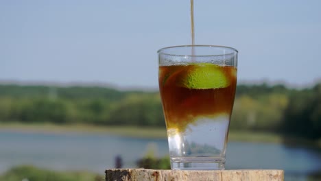 espresso goteando en un vaso de tónico con rodajas de lima - primer plano, enfoque selectivo