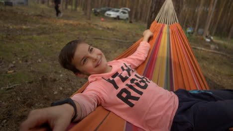 teenager boy enjoying time in swinging hammock in forest.