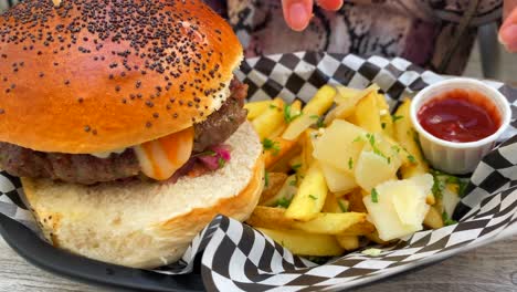 Mojar-Patatas-Fritas-Con-Queso-Parmesano-En-Ketchup-Y-Una-Hamburguesa-Con-Queso-Con-Pan-Brioche,-Comer-Comida-Americana-Poco-Saludable,-Toma-De-4k