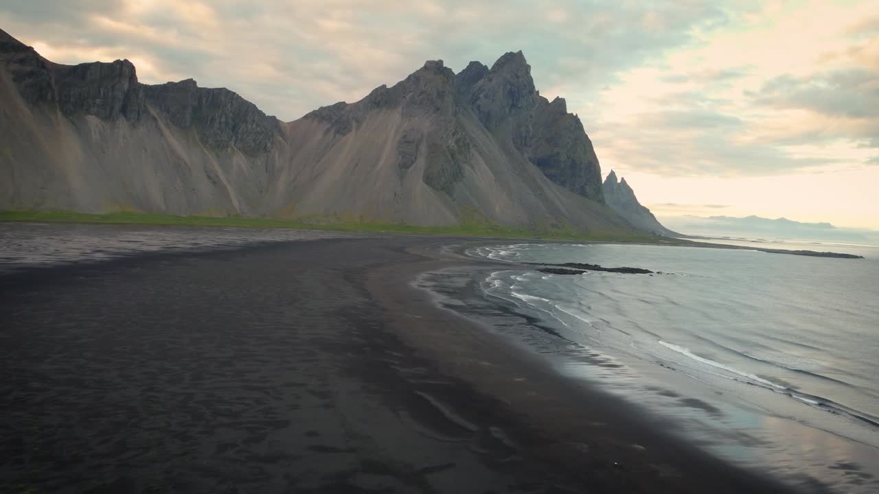 Betagende luftoptagelser viser den sorte sandstrand og de takkede tinder nær Vestrahorn-bjerget på Stokksnes-halvøen, Island. En fascinerende blanding af dramatiske landskaber og skønne udsigter.