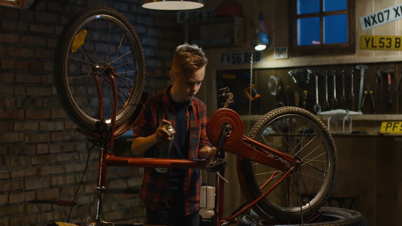Boy Repairing a Red Bicycle in a Garage