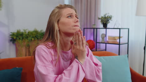 young woman praying sincerely with folded arms asking god for help, begging apology, making a wish