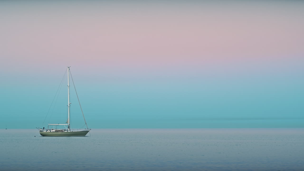 Yacht and swimming man visible from the Mediterranean sea coast in Barcelona at sunset, Spain