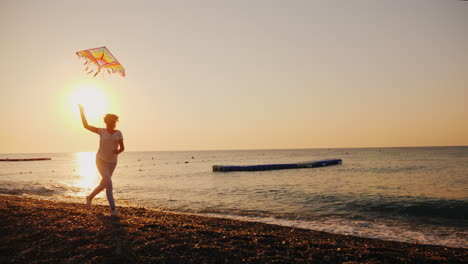 mujer con cometa corre a lo largo de la playa steadicam shot