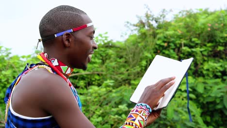 hombre africano, sonriendo, leyendo un libro al aire libre, vistiendo ropa tradicional masai