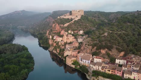 miravet castle and riverside town at ebro river shore