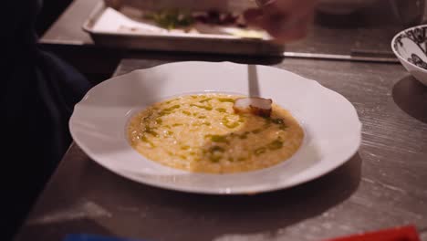 cook in a restaurant puts the fried chicken pieces on the white plate with pasta