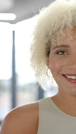 vertical video: smiling woman with curly hair looking at camera in bright office setting