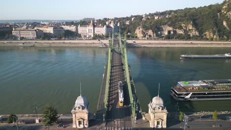 aerial pullback reveals liberty bridge as yellow tram enters frame