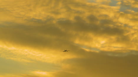 airplane flying in cloudy sunset sky - low angle