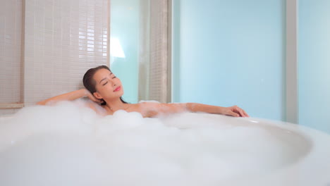 bella mujer relajándose en la bañera espumosa