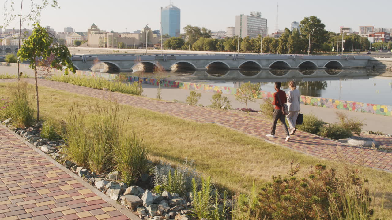Interracial Business Couple Walking along Waterfront
