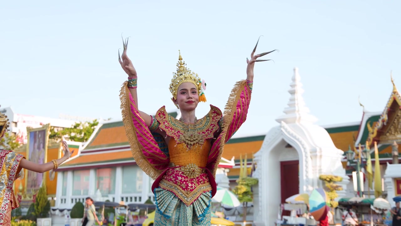 Una ballerina in un elaborato costume tradizionale esegue aggraziati movimenti Khon davanti a un tempio storico.