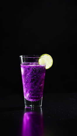 purple sparkling cocktail with lime garnish