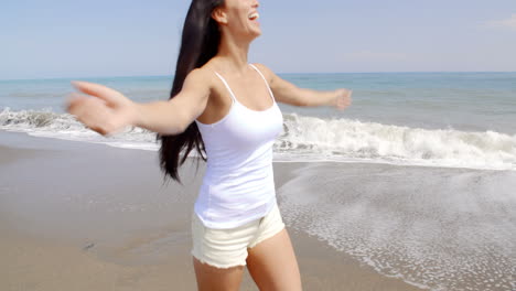 Mujer-Caminando-Por-La-Playa-Ventosa-Con-Las-Manos-En-El-Pelo