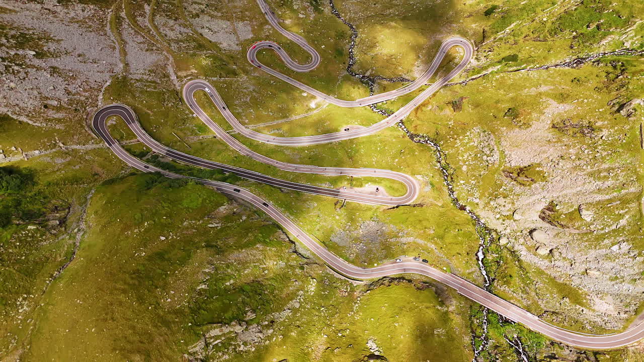 Spectacular Transfagarash highway from drone footage. Vast valley in the Carpathian Mountains, Romania. Narrow river flows along the road