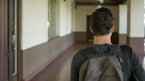 a young caucasian man traveling alone with a backpack walking through a train station hallway at after arriving at his destination