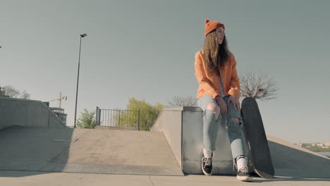 chica patinadora esperando a alguien sentado en un parque de patinaje 1