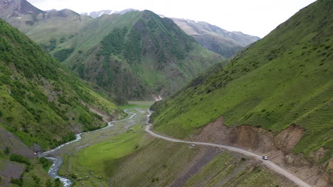 drone shot lowering down to a road in the caucasus mountains leading to juta georgia