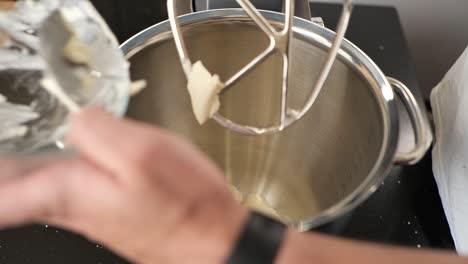 close-up of a baker using a stand mixer to blend buttercream frosting