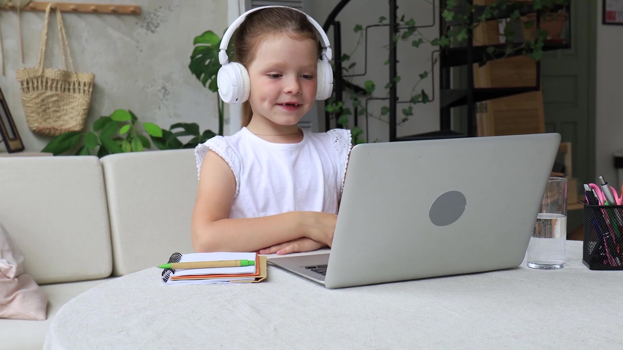 Happy Young Girl in Headphones Engaged in Online Learning on Laptop