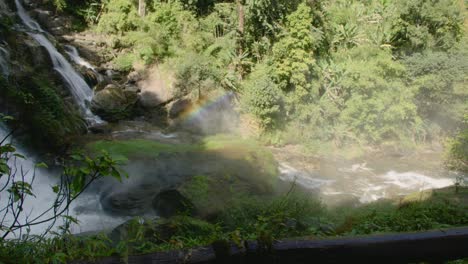 majestic waterfall in a lush green forest with a rainbow mist