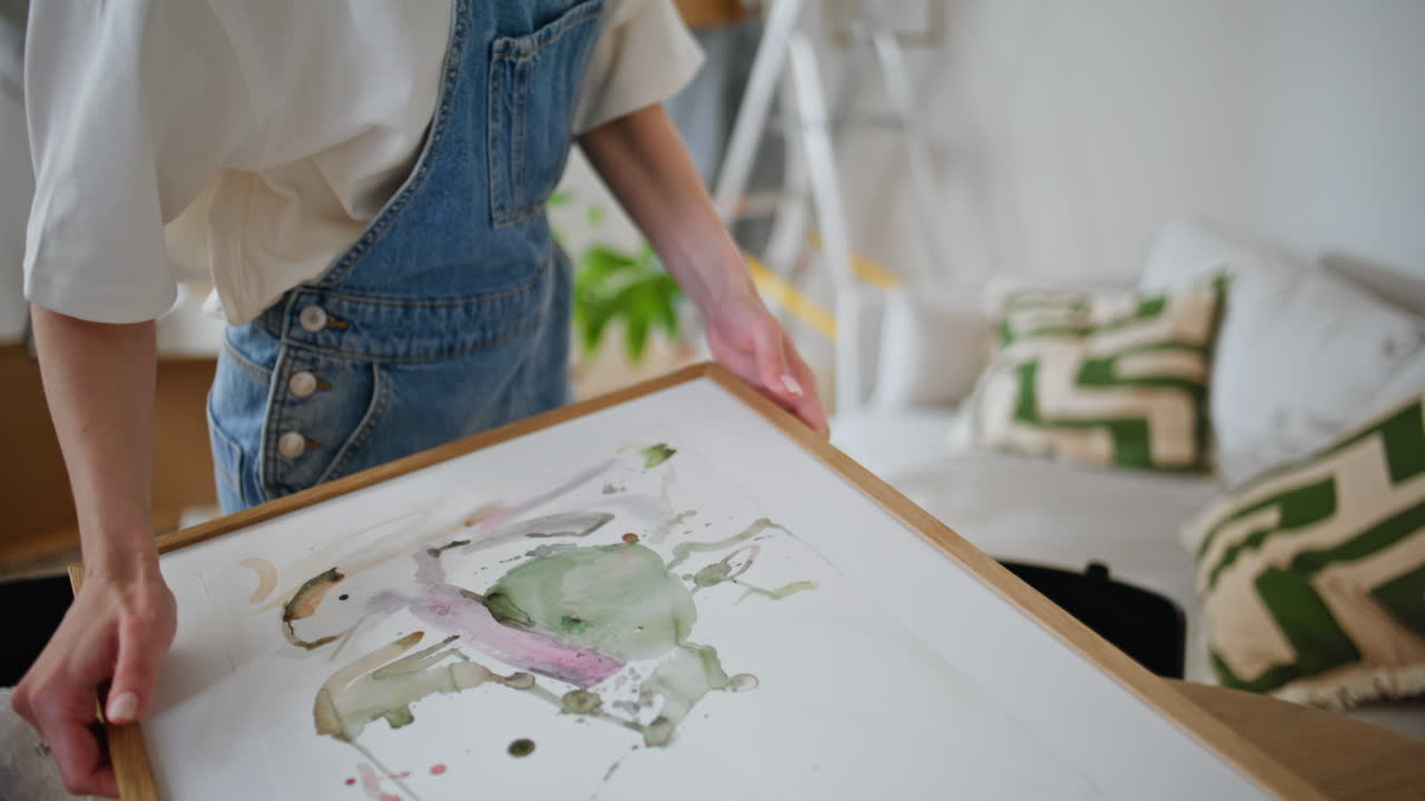 Woman hands taking artwork for decorating living room closeup. Happy family