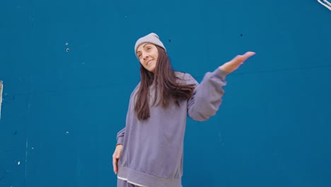 A woman dancing in front of a blue wall