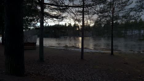 wooden wind shelter cabin in forest next to river, pan